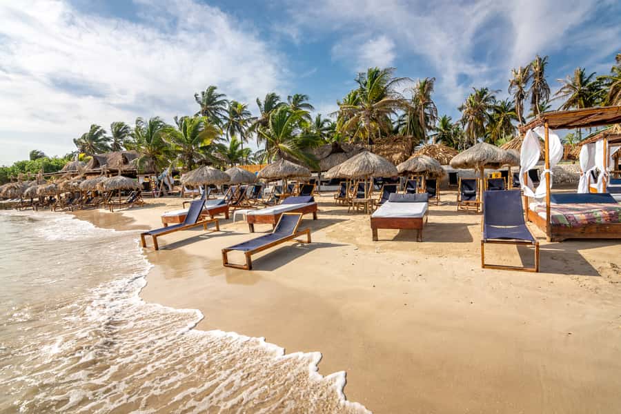 From Cartagena: Palmarito Beach With Buffet Lunch And Pool - Palmarito Beach setup: chairs, kiosks, pool access, and space to breathe